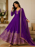 Woman wearing a purple embroidered anarkali suit in a decorated room.